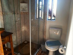 a bathroom with a toilet and a glass shower at Cabana Alto do Monte in Gramado