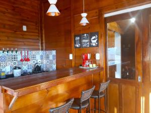 a bar in a restaurant with wooden walls and chairs at Cabana Alto do Monte in Gramado