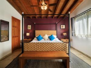 a bedroom with a canopy bed with blue pillows at Hotel Amate del Rio in Malinalco