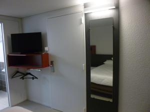 a mirror in a room with a bed and a television at Brit Hotel Mayenne in Mayenne