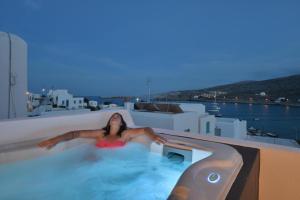 une femme dans un bain à remous au-dessus d'un bâtiment dans l'établissement AMO Folegandros, à Karavostasi