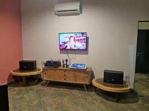 a living room with two tables and a tv on a wall at Monkey Mier LOT 2028 in Kampong Alor Gajah