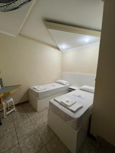 a small room with two beds and a desk at Hotel City II in Santo André