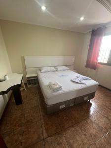 a small bedroom with a bed and a table at Hotel City II in Santo André