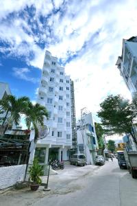wysoki biały budynek na ulicy z palmami w obiekcie Khách sạn Xà Nu w mieście Kon Tum