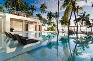 a villa with a swimming pool and palm trees at Amilla Maldives in Kihaadhoo