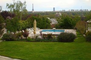 a view of a yard with a pool and a umbrella at Villa House With Panoramic View On Paris in Suresnes