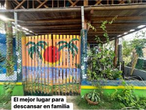 uma cerca com palmeiras pintadas ao lado de um edifício em Cabaña El Paraíso Uveros em San Juan de Urabá