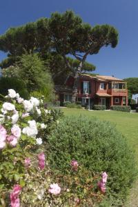 ein Haus mit einem Baum und Blumen im Vordergrund in der Unterkunft Residence Pineta in Albinia