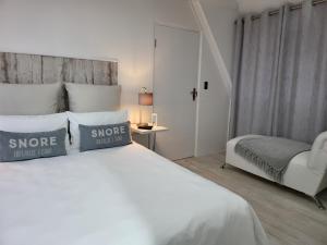a bedroom with a large white bed and a chair at Beach Style Cottage in Langebaan