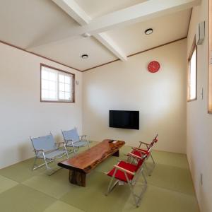 Zimmer mit einem Tisch und Stühlen sowie einem TV in der Unterkunft 赤だすき_別邸 in Hakuba