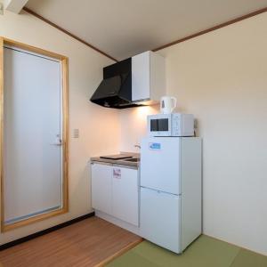 eine Küche mit einem weißen Kühlschrank und einer Mikrowelle in der Unterkunft 赤だすき_別邸 in Hakuba