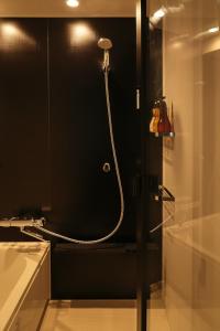 um chuveiro numa casa de banho com uma parede preta em Nplus HOTEL Higashikanda-akihabara em Tóquio