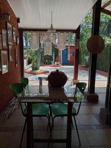 a glass table with green chairs and a vase on it at Casa da Roseli - Pitangueiras in Guarujá