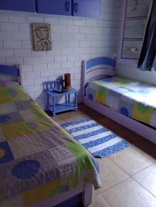 a bedroom with two beds and a table with rugs at Casa da Roseli - Pitangueiras in Guarujá