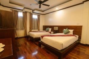 a hotel room with two beds and a ceiling fan at Lux Hotel in Luang Prabang