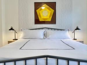 a bedroom with a white bed with a yellow painting at The Clemente Mt. Washington by Luxe PGH in Pittsburgh