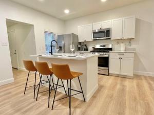 a kitchen with white cabinets and a kitchen island with chairs at The Clemente Mt. Washington by Luxe PGH in Pittsburgh