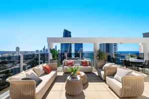 a patio with couches and tables on a roof at Biarritz Apartments in Gold Coast