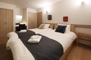 twee bedden in een hotelkamer met handdoeken erop bij Wonderland Furano Maple in Furano