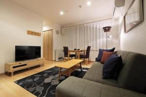 een woonkamer met een bank, een tv en een tafel bij Wonderland Furano Maple in Furano