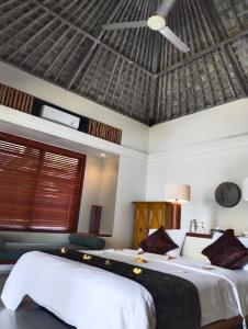 a bedroom with two beds and a ceiling at Villa Bukit Segara in Amed