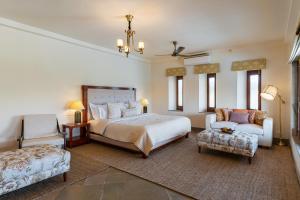 a bedroom with a bed and a couch and a chair at Chunda Shikar Oudi in Udaipur