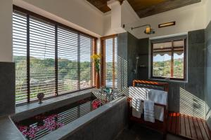 a bathroom with a tub and a large window with a view at Chunda Shikar Oudi in Udaipur