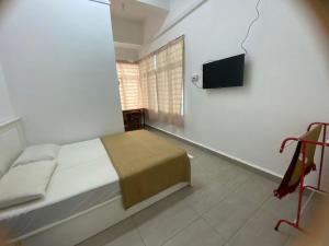 a bedroom with a bed and a flat screen tv at Roomstay Gemilang in Kuala Terengganu