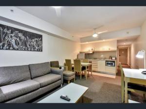 a living room with a couch and a table and a kitchen at Pandanas Apt 3 (Darwin CBD, Harbour views) in Darwin