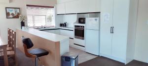 a kitchen with white cabinets and a white refrigerator at Spacious Home with Awesome Lake Views in Queenstown