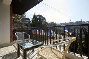 a table and two chairs on a balcony with flags at Bandipur Bliss-Apartment in Bandipur