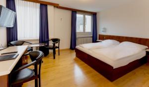 バーデンにあるHotel Linde - 24h Self Check-inのベッド、デスク、椅子が備わるホテルルームです。