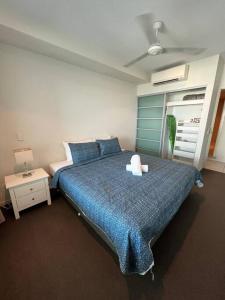 a bedroom with a large bed with a blue comforter at Above & Beyond (21st floor two bedrooms apartment) in Darwin