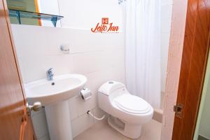 a white bathroom with a toilet and a sink at Hotel Leito Inn in Tarapoto