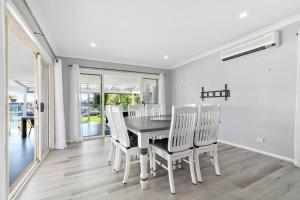 a dining room with a table and white chairs at Voyagers Resort - Stunning home! in Banksia Beach