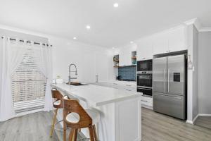 a white kitchen with a counter and a refrigerator at Voyagers Resort - Stunning home! in Banksia Beach