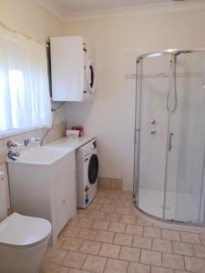 a bathroom with a shower and a washing machine at Wagga Showground Villas in Wagga Wagga