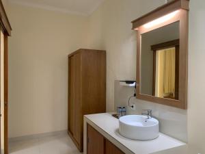 a bathroom with a white sink and a mirror at Betesda Guest House in Canggu