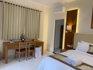 a hotel room with a desk and a bed at Betesda Guest House in Canggu