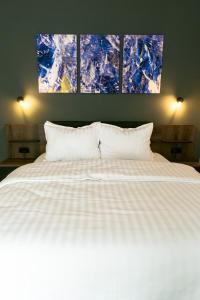 ein Schlafzimmer mit einem weißen Bett mit drei Gemälden an der Wand in der Unterkunft Hotel boutique Danifeld Inn in Woronetz
