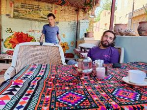 two men sitting at a table with a table cloth on it at Shiva Guest House in Jaisalmer