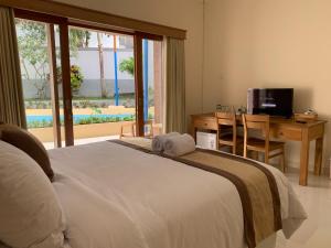a bedroom with a bed and a desk and a television at Betesda Guest House in Canggu