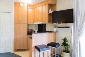 a kitchen with wooden cabinets and a refrigerator and stools at Gem in the Heart of Mooloolaba - Landmark Resort in Mooloolaba