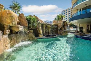 a swimming pool in a resort with a waterfall at Gem in the Heart of Mooloolaba - Landmark Resort in Mooloolaba