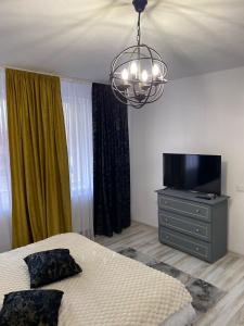 アルバ・ユリアにあるGarsoniera Mariaのベッドルーム(ベッド1台、テレビ、シャンデリア付)