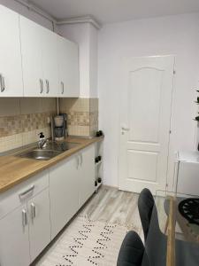 アルバ・ユリアにあるGarsoniera Mariaの白いキャビネット、シンク、ドア付きのキッチン