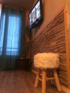 Zimmer mit einem Stuhl und einem TV an einer Backsteinwand in der Unterkunft Les Marmottes 2 in Orcières