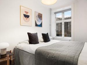 a white bedroom with a large bed and a window at Sanders Stage - Enchanting Four-Bedroom Apartment Near Nyhavn in Copenhagen