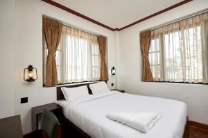 um quarto com uma grande cama branca e 2 janelas em Bandipur Bliss -- Villa - Hotel - Apartment - Cottage em Tanahun